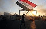 An Iraqi protester waves the national flag during a demonstration against state corruption, failing public services, and unemployment, in the Iraqi capital Baghdad on October 5, 2019. (AHMAD AL-RUBAYE/AFP)