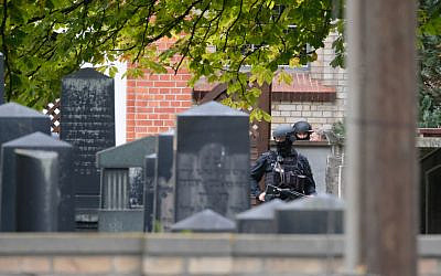 Policemen are seen behind gravestones of a Jewish cemetery close to the site of a shooting in Halle an der Saale, eastern Germany, on October 9, 2019 (Sebastian Willnow/dpa/AFP)