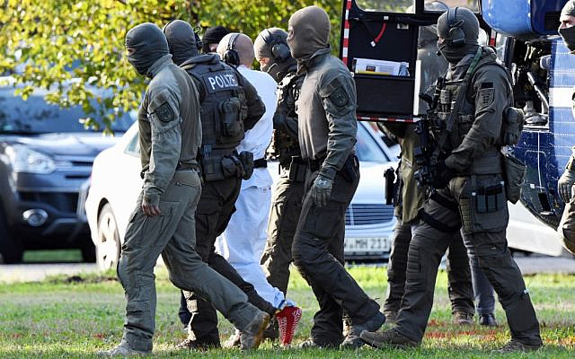 A person believed to be the suspect in the Halle shooting is escorted by policemen after landing in a helicopter at the Federal Supreme Court in Karlsruhe, (Uli Deck / dpa / AFP)