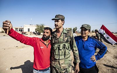 Locals welcome Syrian regime forces as they arrive at the western entrance of the town of Tal Tamr, in the countryside of Syria's northeastern Hasakeh province, on October 14, 2019. (Delil Souleiman/AFP)