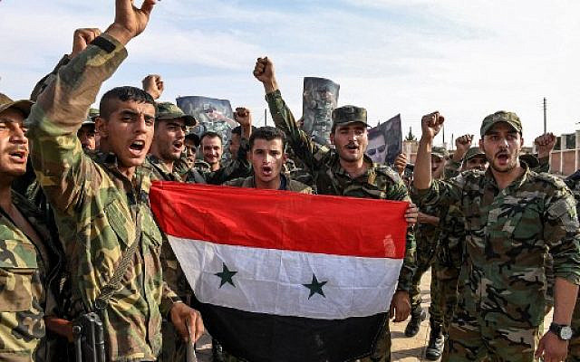 Syrian government soldiers chanting slogans as they pose for a group photo with a national flag and portraits of President Bashar Assad on the outskirts of the northern city of Manbij in the north of Aleppo province as government forces deploy there on October 15, 2019. (AFP) Syrian government soldiers chanting slogans as they pose for a group photo with a national flag and portraits of President Bashar Assad on the outskirts of the northern city of Manbij in the north of Aleppo province as government forces deploy there on October 15, 2019. (AFP)