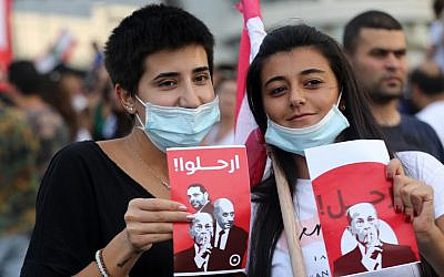 Women wave signs reading "leave" in Arabic and showing the faces of Lebanon's President Michel Aoun, Prime Minister Saad Hariri, and Parliament Speaker Nabih Berri, during a protest outside the presidential palace in Baabda, east of the capital Beirut, on October 18, 2019.  (Anwar Amro/AFP)