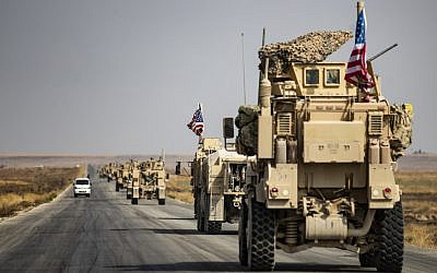 US military vehicles drive on a street in the town of Tal Tamr on October 20, 2019, after pulling out of their base. (Photo by Delil SOULEIMAN / AFP)