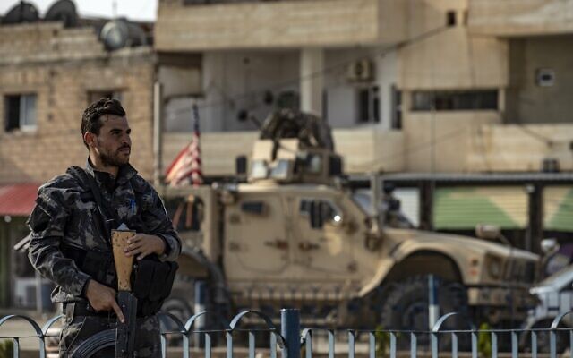 A fighter from the Syrian Democratic Forces SDF stands guard as a US military vehicle pulling out of a US forces base in the Northern Syrian town of Tal Tamr drives by, on October 20, 2019. (Delil SOULEIMAN / AFP) A fighter from the Syrian Democratic Forces SDF stands guard as a US military vehicle pulling out of a US forces base in the Northern Syrian town of Tal Tamr drives by, on October 20, 2019. (Delil SOULEIMAN / AFP)