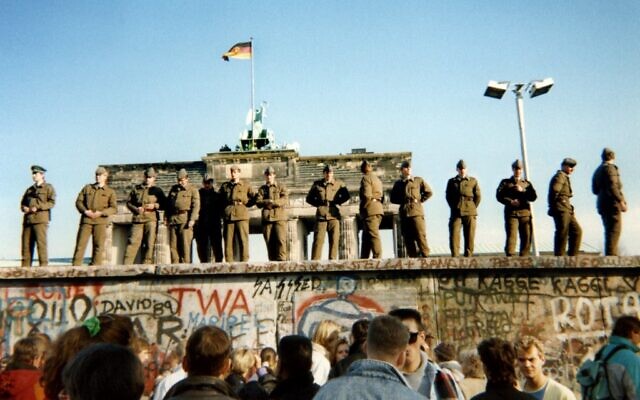 In this file photo taken on November 11, 1989, East German border guards stand on a section of the Berlin wall with the Brandenburg gate in the background in Berlin. (Gunther Kern/AFP)