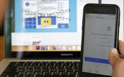 A picture taken on October 23, 2019, shows a Palestinian man holding a cell phone displaying the message "this website is not accessible," at an office in the city of Hebron in the West Bank, following a Ramallah court's ruling to block access to dozens of websites. (HAZEM BADER / AFP)
