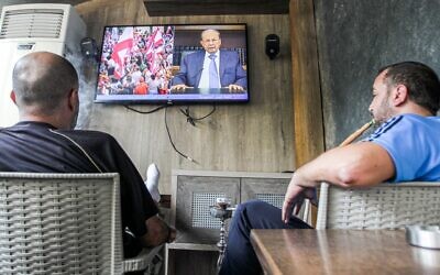 Lebanese men smoke a hookah as they watch a televised speech by President Michel Aoun, at a cafe in the capital Beirut on October 24, 2019, as Aoun addresses demonstrators on the eighth day of protests against tax increases and official corruption. (Photo by IBRAHIM  AMRO / AFP)