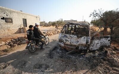 Syrians ride a motorcycle past a burnt vehicle near the site where a helicopter gunfire reportedly killed nine people, including Islamic State leader Abu Bakr al-Baghdadi, near the northwestern Syrian village of Barisha in the Idlib province along the border with Turkey, October 27, 2019. (Photo by Omar HAJ KADOUR / AFP)