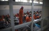 Men, allegedly affiliated with the Islamic State terror group, sit on the floor in a prison in the northeastern Syrian city of Hasakeh, on October 26, 2019. (Fadel Senna/AFP)