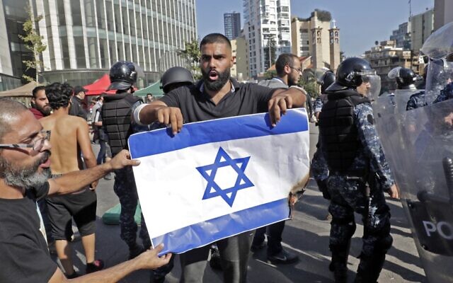 Lebanese protesters set the Israeli flag ablaze as riot police officers remove anti-government protesters blocking the road at the ring-bridge in the Lebanese capital Beirut on October 31, 2019 (ANWAR AMRO / AFP)