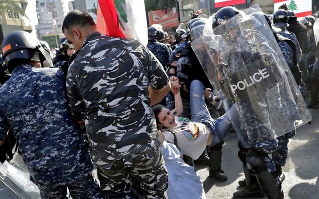 Lebanese riot police officers remove anti-government protesters as they dismantle a roadblock in the ring-bridge in the Lebanese capital Beirut on October 31, 2019 (ANWAR AMRO / AFP)