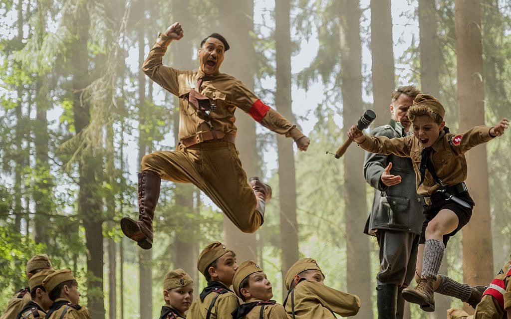Taika Waititi, center, playing Hitler, wrote and directed 'Jojo Rabbit.' Roman Griffin Davis, jumping to his right, co-stars. (Kimberley French/Twentieth Century Fox Film Corp. via JTA)