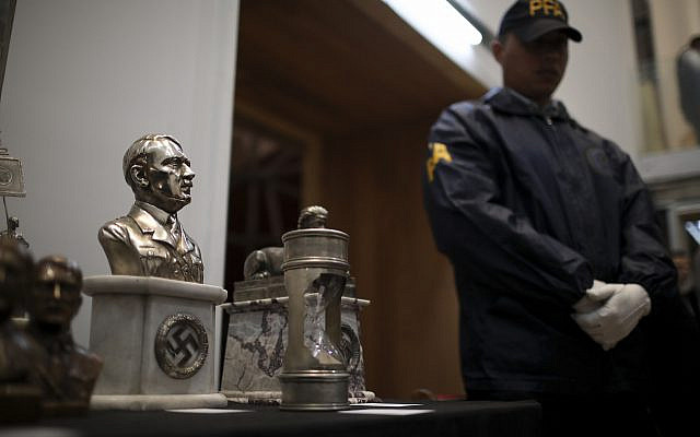 A police officer stands in front of a cache of Nazi artifacts discovered in 2017, during a press conference in Buenos Aires, Argentina, October 2, 2019. (Natacha Pisarenko/AP)