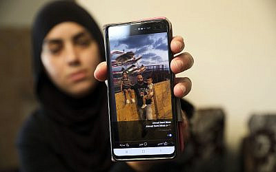 A relative on October 7, 2019, shows a photo of Ahmed Manaa with his children at the family home in Majd al-Krum, Israel. Two brothers, Ahmed and Khalil Manaa, and a third man, Mohammed Sabea, were killed in a midday shootout in Majd al-Krum, that left another Manaa brother wounded. (AP Photo/Mahmoud Illean)