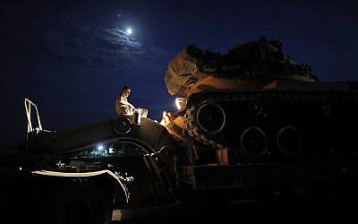 A Turkish army officer prepares to upload a tank from a truck to its new position on the Turkish side of the border between Turkey and Syria, in Sanliurfa province, southeastern Turkey, Tuesday, Oct. 8, 2019. . (AP Photo/Lefteris Pitarakis)