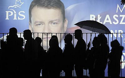 In this photo taken on September 26, 2019, supporters of Poland's ruling right-wing party are standing in line before a candidate's billboard to get to a party convention in Warsaw, Poland, ahead of the parliamentary election in which the Law and Justice party is hoping to win a second term in power. (AP/Czarek Sokolowski)