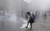A protester kicks a tear gas canister during clashes with police in Santiago, Chile, October 20, 2019. (AP Photo/Esteban Felix)