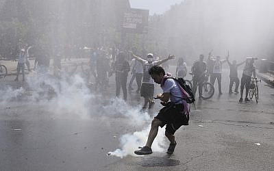 A protester kicks a tear gas canister during clashes with police in Santiago, Chile, October 20, 2019. (AP Photo/Esteban Felix)