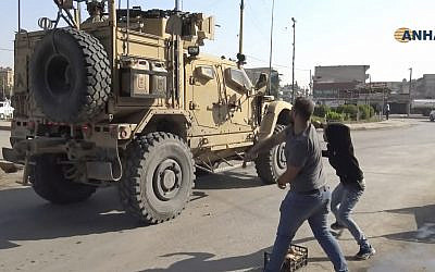 In this frame grab from video provided by Hawar News, ANHA, the Kurdish news agency, residents who are angry over the US withdrawal from Syria hurl potatoes at American military vehicles in the town of Qamishli, northern Syria, October 21, 2019. (ANHA via AP)