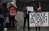 Pro-Brexit campaigners stand under umbrellas with their placards outside the Houses of Parliament in London, October 21, 2019. (Alastair Grant/AP)