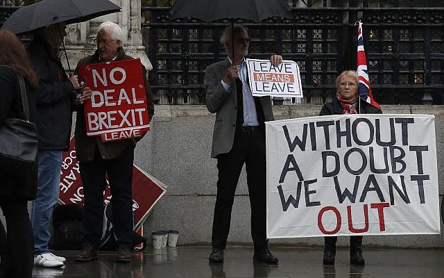 Pro-Brexit campaigners stand under umbrellas with their placards outside the Houses of Parliament in London, October 21, 2019. (Alastair Grant/AP) Pro-Brexit campaigners stand under umbrellas with their placards outside the Houses of Parliament in London, October 21, 2019. (Alastair Grant/AP)