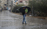 A Palestinian man holds a child under an umbrella during rainfall in Gaza City, October 26, 2019. (AP Photo/ Hatem Moussa)