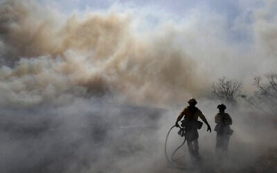 Firefighters walk through a cloud of smoke as winds fuel the Easy Fire Wednesday, Oct. 30, 2019, in Simi Valley, Calif. Fire officials say they're investigating the cause of the fire. (AP Photo/Marcio Jose Sanchez)