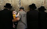 A Jewish man holds a child as he participates in morning prayers before the beginning of the Jewish holiday of Yom Kippur, at the Western Wall, Judaism's holiest site in Jerusalem's Old City, Wednesday, Oct. 8, 2008. (AP Photo/Kevin Frayer)