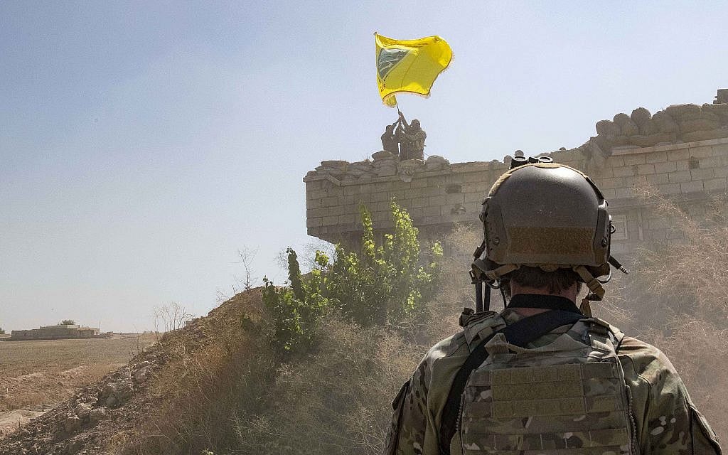 In this photo from September 21, 2019, released by the US Army, a US soldier oversees members of the Syrian Democratic Forces as they demolish a Kurdish fighters' fortification and raise a Tal Abyad Military Council flag over the outpost as part of the so-called "safe zone" near the Turkish border. (U.S. Army photo by Staff Sgt. Andrew Goedl via AP)