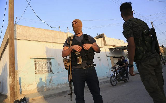 In this photo from October 10, 2019, Syrian Democratic Forces fighters stand guard in the town of Qamishli, Syria (AP Photo/Baderkhan Ahmad) In this photo from October 10, 2019, Syrian Democratic Forces fighters stand guard in the town of Qamishli, Syria (AP Photo/Baderkhan Ahmad)