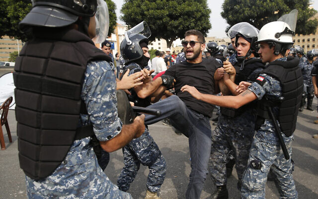 Police remove an anti-government protester blocking a main highway with his body in Beirut, Lebanon, October 26, 2019 (AP Photo/Hussein Malla) Police remove an anti-government protester blocking a main highway with his body in Beirut, Lebanon, October 26, 2019 (AP Photo/Hussein Malla)