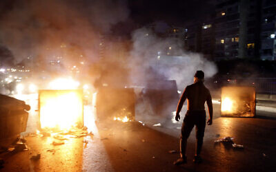 A supporter of Lebanese Prime Minister Saad Hariri burns garbage containers to block  a main road, in Beirut, Lebanon, October 29, 2019. (AP Photo/Bilal Hussein)