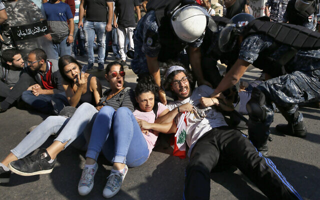 Anti-government protesters lie on a road, as they scream and hold each others while riot police try to remove them and open the road, in Beirut, Lebanon, Oct. 31, 2019 (AP Photo/Bilal Hussein)
