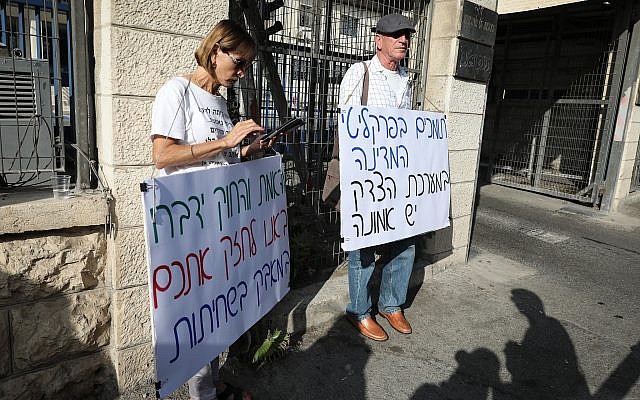 Protesters hold signs expressing support for prosecutors outside the Justice Ministry headquarters on October 2, 2019, ahead of Prime Minister Benjamin Netanyahu's pre-indictment hearing. (Noam Rivkin Fenton/Flash90)