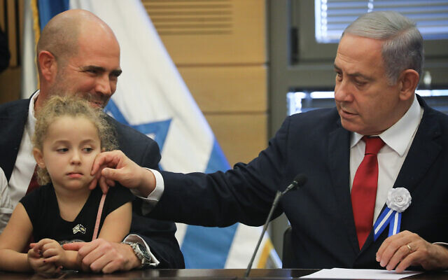 Then-prime minister Benjamin Netanyahu leads a Likud faction meeting at the opening of the 22nd Knesset, on October 3, 2019. Next to him is then-justice minister Amir Ohana with one of his children. (Hadas Parush/Flash90) Then-prime minister Benjamin Netanyahu leads a Likud faction meeting at the opening of the 22nd Knesset, on October 3, 2019. Next to him is then-justice minister Amir Ohana with one of his children. (Hadas Parush/Flash90)