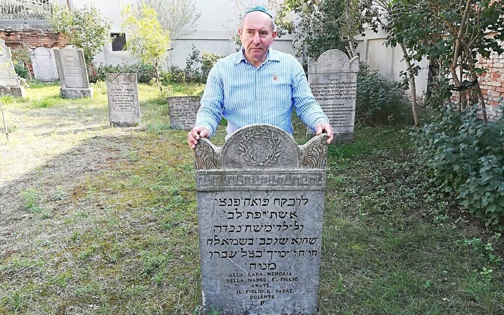 Giuseppe Minera next to a tombstone in the Jewish cemetery of Ostiano, Italy. (Giovanni Vigna/ Times of Israel)