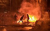 Lebanese demonstrators stand by a fire a make-shift barricade amid clashes with security forces during a mass protest at Riad al-Solh Square in Beirut on October 18, 2019. (STR/AFP)