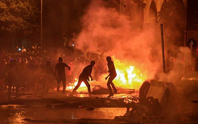 Lebanese demonstrators stand by a fire a make-shift barricade amid clashes with security forces during a mass protest at Riad al-Solh Square in Beirut on October 18, 2019. (STR/AFP) Lebanese demonstrators stand by a fire a make-shift barricade amid clashes with security forces during a mass protest at Riad al-Solh Square in Beirut on October 18, 2019. (STR/AFP)