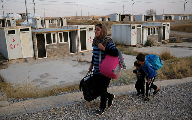 Salwa Hanna with her children, who are newly displaced by the Turkish military operation in northeastern Syria, carry their belongings after they arrive at the Bardarash refugee camp, north of Mosul, Iraq, October 17, 2019. (AP Photo/Hussein Malla) Salwa Hanna with her children, who are newly displaced by the Turkish military operation in northeastern Syria, carry their belongings after they arrive at the Bardarash refugee camp, north of Mosul, Iraq, October 17, 2019. (AP Photo/Hussein Malla)