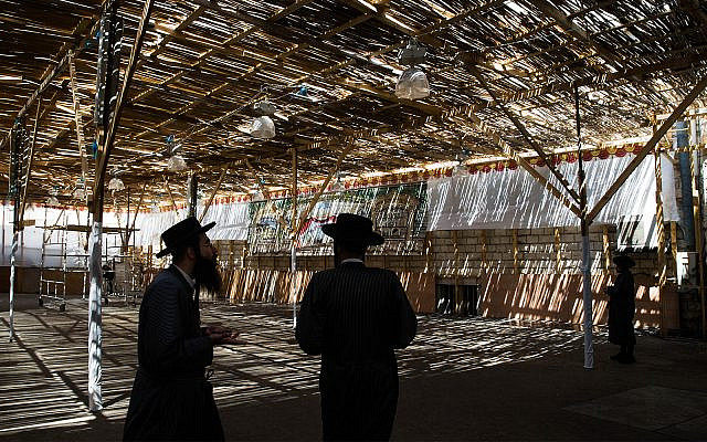 Illustrative: Jews in a sukkah in Jerusalem, September 21, 2015. (Nati Shohat/Flash90)