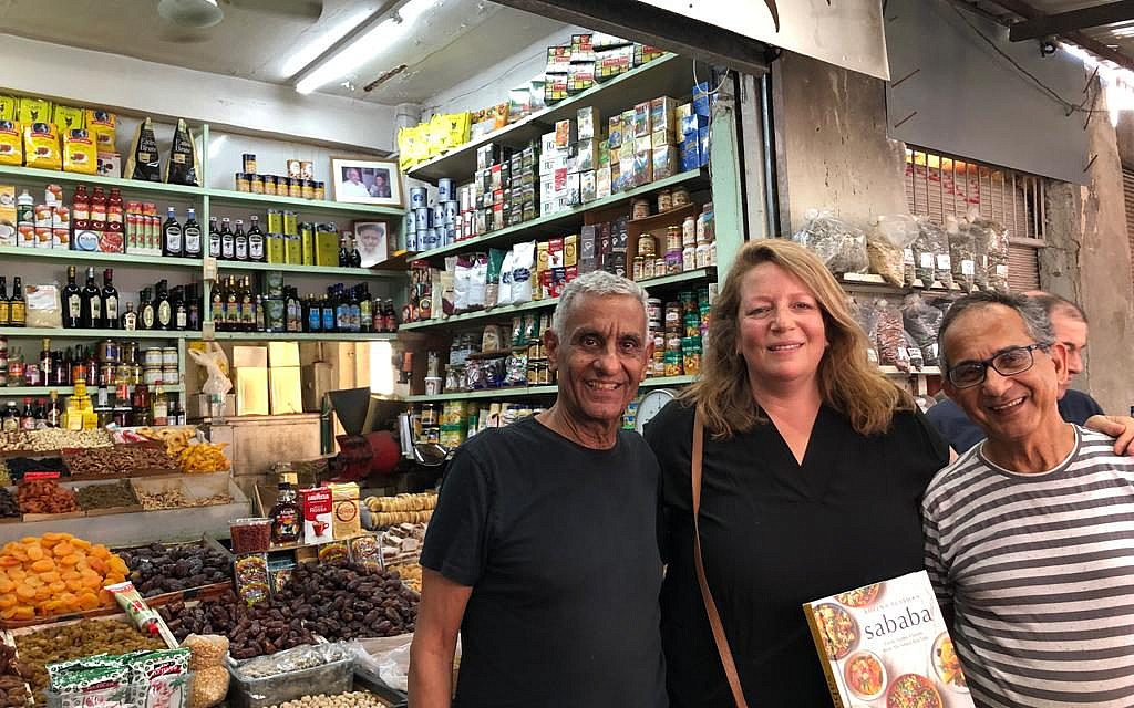 Cookbook author Adeena Sussman (center) with a copy of 'Sababa' and the Amrani brothers in the Carmel Market (Jessica Steinberg/Times of Israel) Cookbook author Adeena Sussman (center) with a copy of 'Sababa' and the Amrani brothers in the Carmel Market (Jessica Steinberg/Times of Israel)