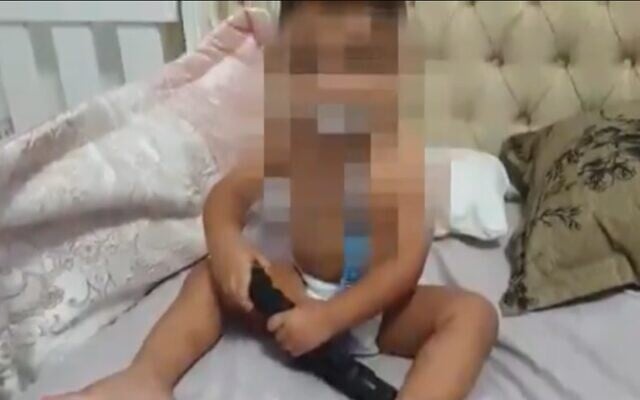 An 18-month-old baby is filmed playing with a gun in his crib in the northern city of Umm al-Fahm. (screen capture: Kan public broadcaster) An 18-month-old baby is filmed playing with a gun in his crib in the northern city of Umm al-Fahm. (screen capture: Kan public broadcaster)
