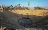 Palestinians walk around a crater caused by an Israeli airstrike launched in response to rocket fire, in Khan Younis in the southern Gaza Strip, November 2, 2019. (Said Khatib/AFP)