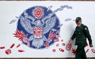 A member of Iran's Revolutionary Guards walks past a new mural painted on the walls of the former US embassy in the capital Tehran on November 2, 2019. (Atta Kenare/AFP)