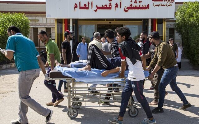 Iraqi youths push a man with an injured leg on a gurney outside the gate to Umm Qasr hospital in the southern Iraqi port city on November 5, 2019, after security forces attempted to break up crowds blocking the road to the port earlier in the day. (Photo by Hussein FALEH / AFP) Iraqi youths push a man with an injured leg on a gurney outside the gate to Umm Qasr hospital in the southern Iraqi port city on November 5, 2019, after security forces attempted to break up crowds blocking the road to the port earlier in the day. (Photo by Hussein FALEH / AFP)