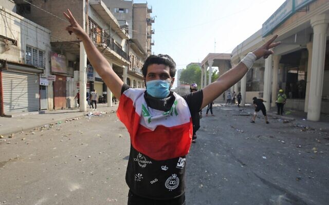 An Iraqi protester wearing a surgical mask gestures during clashes with security forces near the central bank in the capital Baghdad on November 7, 2019, amid ongoing anti-government protests. (AHMAD AL-RUBAYE / AFP) An Iraqi protester wearing a surgical mask gestures during clashes with security forces near the central bank in the capital Baghdad on November 7, 2019, amid ongoing anti-government protests. (AHMAD AL-RUBAYE / AFP)