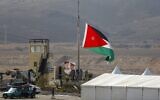 A picture taken from the Israeli side of the border shows Jordanian soldiers raising the national flag ahead of a ceremony at the Jordan Valley site of Naharayim, November 10, 2019. (Menahem Kahana/AFP)