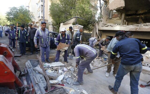 Syrian municipality workers clear debris from building in Damascus' Mazze neighborhood following an airstrike attributed to Israel, November 12, 2019 (LOUAI BESHARA / AFP)
