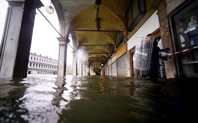 A Carabinieri police officer (R) holding his transparent plexiglass anti-riot shield walks across a flooded arcade by St. Mark's Square on November 15, 2019 in Venice, two days after the city suffered its highest tide in 50 years (Filippo MONTEFORTE / AFP) A Carabinieri police officer (R) holding his transparent plexiglass anti-riot shield walks across a flooded arcade by St. Mark's Square on November 15, 2019 in Venice, two days after the city suffered its highest tide in 50 years (Filippo MONTEFORTE / AFP)