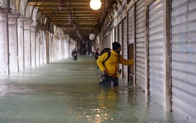 A man stands by a closed shop in a flooded arcade by St. Mark's square on November 15, 2019 in Venice, two days after the city suffered its highest tide in 50 years  ( Filippo MONTEFORTE / AFP)